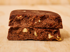 Two Chocolate Sea Salt protein bars with visible nut chunks, stacked on a light wooden surface, enriched with marine collagen for an added boost.
