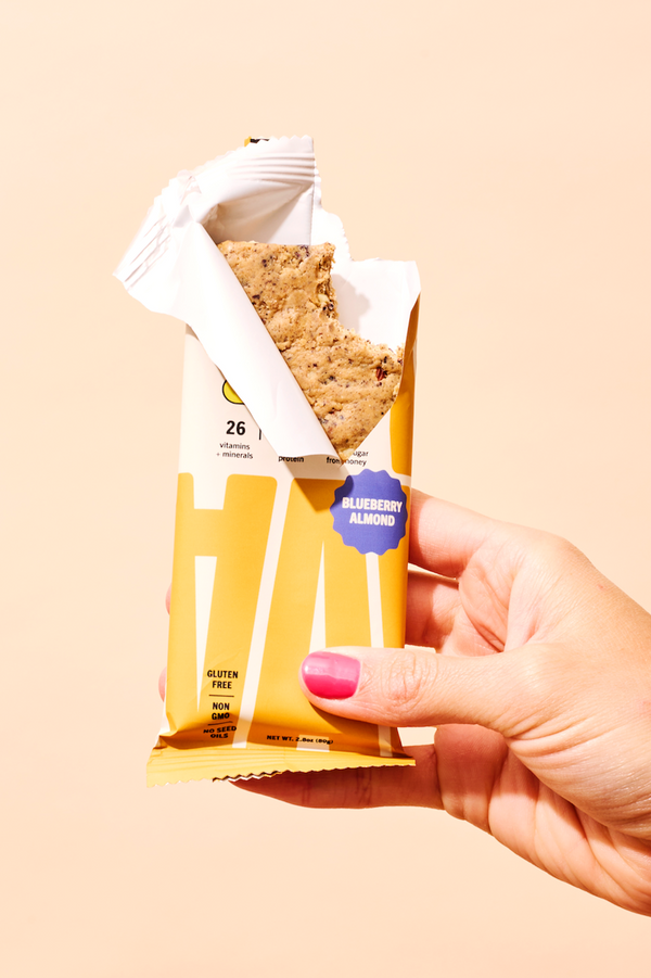 Hand holding an opened ABC 360® Blueberry Almond Protein Meal Bar, showing the inside